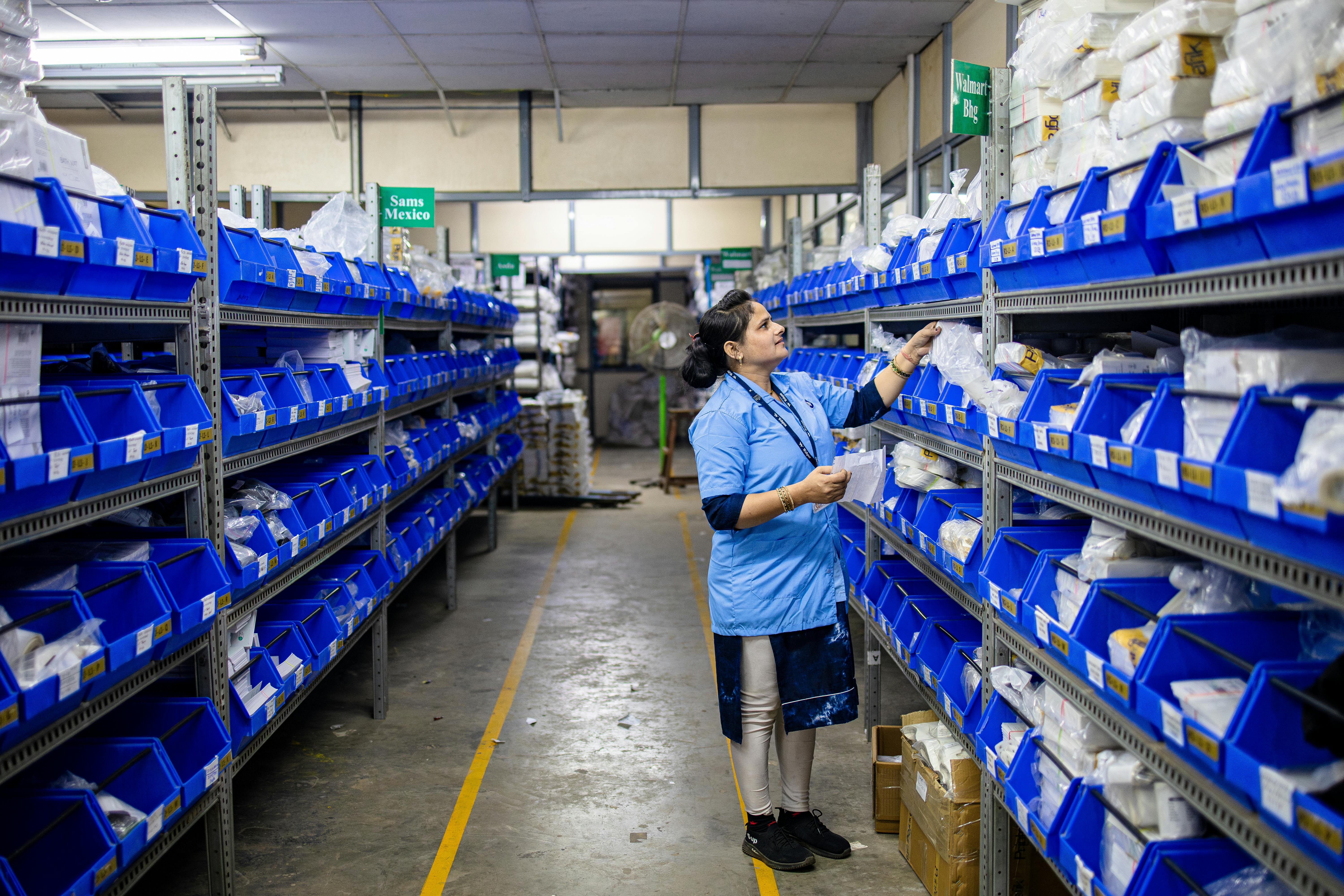 Female worker organising inventory on shelves in a warehouse, illustrating our warehousing services